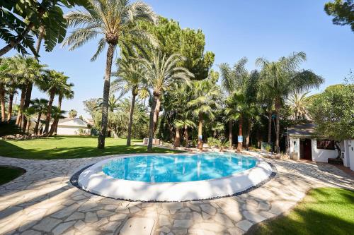 a swimming pool in a yard with palm trees at El Oasis Villa Resort in La Eliana