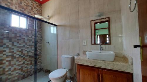 La salle de bains est pourvue de toilettes, d'un lavabo et d'une douche. dans l'établissement Casa temporada em Prado-BA ótimo preço, à Prado