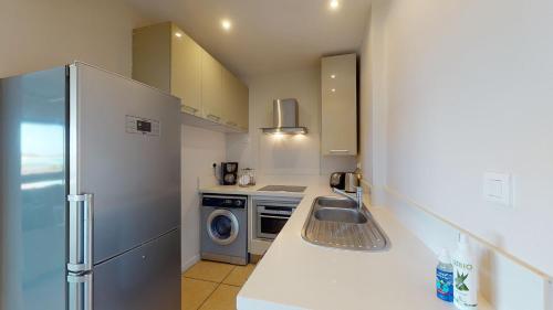 a small kitchen with a refrigerator and a sink at Bon Azur Beachfront Suites & Penthouses with LOV in Trou aux Biches