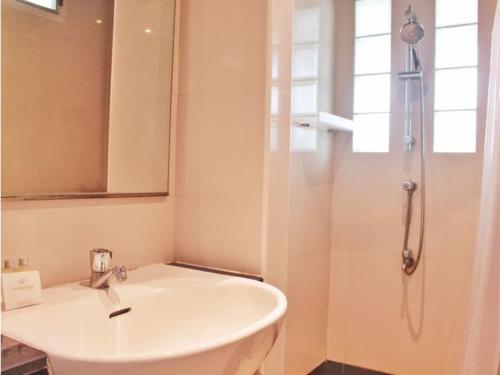 a white bathroom with a sink and a shower at The Finn Hotel / เดอะฟินน์โฮเทล in Ban Liap