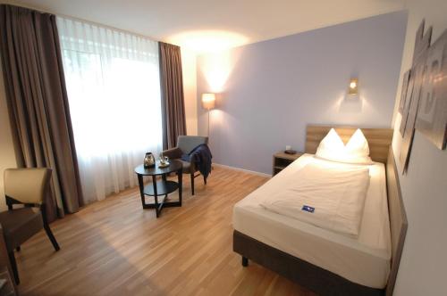 a hotel room with a bed and a small table at Kempe Komfort plus Hotel in Solingen