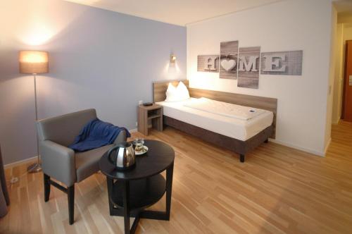 um quarto com uma cama, uma cadeira e uma mesa em Kempe Komfort plus Hotel em Solingen