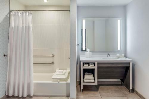 a bathroom with a shower and a sink and a mirror at Embassy Suites by Hilton Atlanta Midtown in Atlanta
