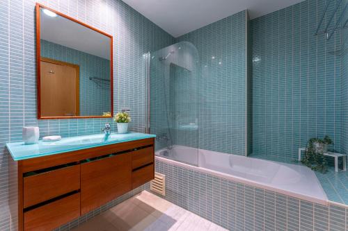 een badkamer met een bad, een wastafel en een spiegel bij Apartamento Stella Maris in Olhão