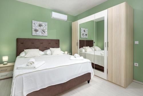 ein grünes Schlafzimmer mit einem großen Bett und einem Spiegel in der Unterkunft Guest house LUCIJA with swimming pool in Tugare