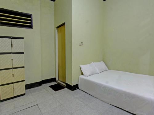 1 dormitorio con cama blanca y puerta en SPOT ON 92882 Penginapan 3 Bersaudara, en Kuta Lombok