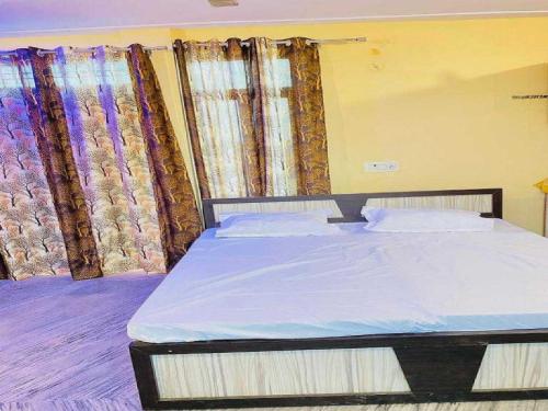 a bed in a room with curtains in a room at Hotel O Apna Hotel And Restaurant in Rewāri