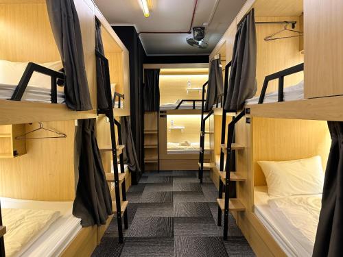 a corridor of a dorm room with bunk beds at THE ROOM Capsule Hotel in Singapore