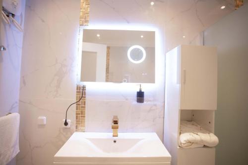 a white bathroom with a sink and a mirror at JQ.APARTMENTS in Accra