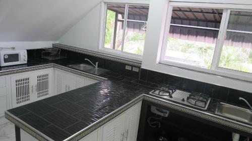a kitchen with black counter tops and two windows at Villa Nap Dau Crown - 8 Br Private Pool Villa - Chalong in Chalong 
