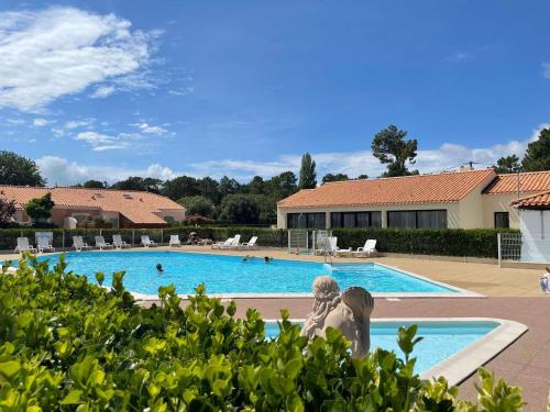 deux femmes assises devant une piscine dans l'établissement Charmante Maison 3 Pièces avec Piscines Chauffées, Terrasse et Jardin, à 300m de la Plage des Demoiselles - FR-1-224C-266, à Saint-Jean-de-Monts