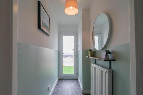 a hallway with a door and a mirror at Coorie by the Coast - Arbroath in Arbroath