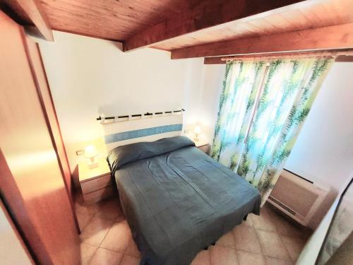 a small bedroom with a bed and a window at SU BISU Costa Rei R4991 terrace with sea view, 500m from the beach in Costa Rei