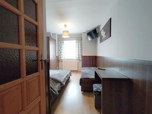 a room with two beds and a desk and a window at Góralski Dworek in Biały Dunajec