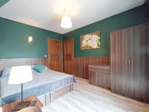 a bedroom with green walls and a bed and a lamp at Góralski Dworek in Biały Dunajec