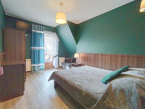a bedroom with a large bed with a green wall at Góralski Dworek in Biały Dunajec