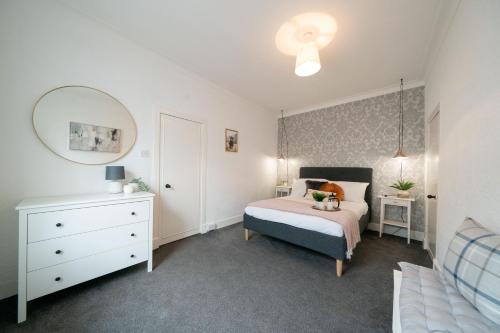 a bedroom with a bed and a dresser and a mirror at Coorie by the Coast, Direct Beach Access Getaway - Arbroath in Arbroath