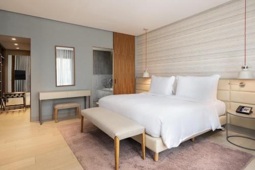 a bedroom with a large white bed and a living room at Radisson Blu Marrakech, Carré Eden in Marrakech