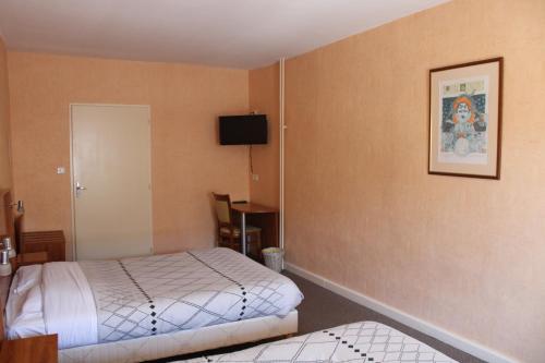 DompaireにあるLe Commerceのベッドルーム1室(ベッド1台、壁掛けテレビ付)