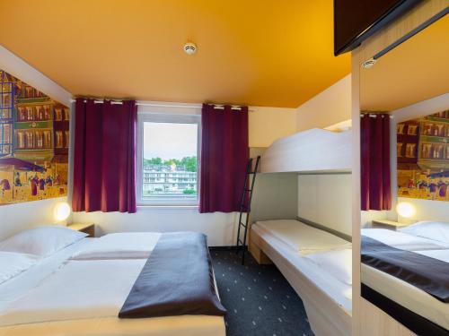 1 dormitorio con 2 literas y ventana en B&B Hotel Düsseldorf-City, en Düsseldorf