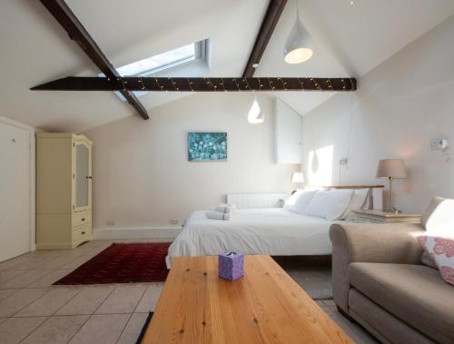 a white bedroom with a bed and a couch at Peaceful, country setting in Suffolk, near coast in Halesworth