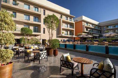 a hotel patio with tables and chairs and a pool at Radisson Blu Marrakech, Carré Eden in Marrakech