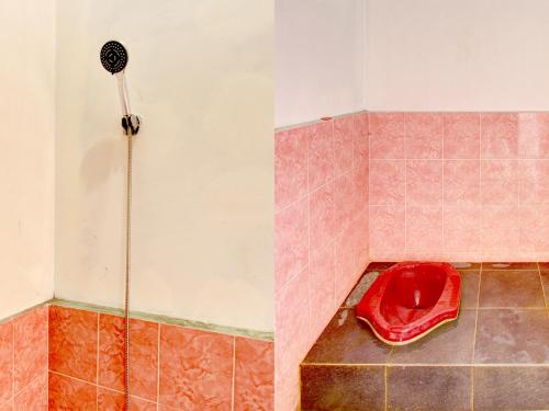 La salle de bains est pourvue d'une douche avec un bol rouge. dans l'établissement SPOT ON 92850 Cindelaras B&b Bunk Bed, à Piyungan