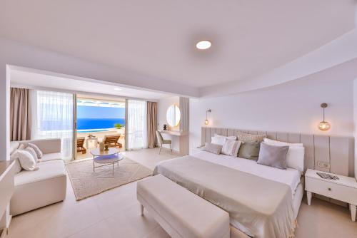 a white bedroom with a large bed and a room with the ocean at La Kumsal Hotel in Kas