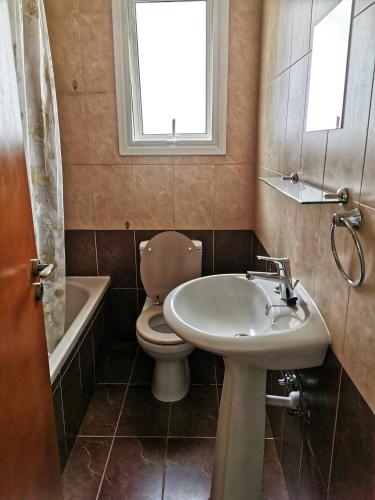 a bathroom with a sink and a toilet and a window at Flemigks 1 bedroom appartement in Larnaka