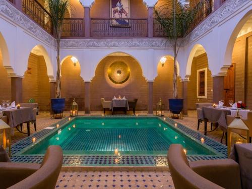 uma piscina num restaurante com mesas e cadeiras em Riad Magda & Spa em Marraquexe