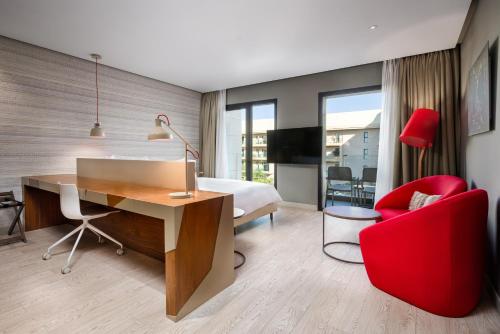 a bedroom with a desk and a bed and a red chair at Radisson Blu Marrakech, Carré Eden in Marrakech