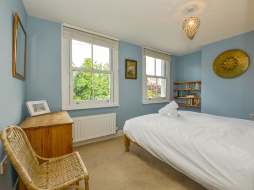 a bedroom with a bed and a desk and two windows at 5 Exe Street in Exeter