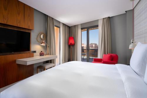 a hotel room with a white bed and a red chair at Radisson Blu Marrakech, Carré Eden in Marrakech