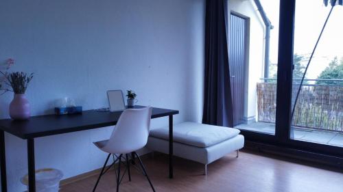 escritorio y silla en una habitación con ventana en Budget Suite mit Balkon - Privatzimmer in Wohnung - NETFLIX & MINIBAR INKLUSIVE, en Coblenza