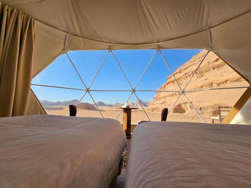 two beds in a tent with a view of the desert at Mouna Luxury Rum Camp in Wadi Rum