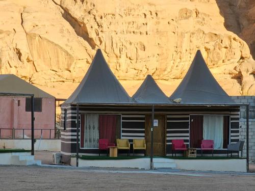 a house in the desert with red chairs and a mountain at Sun Luxury Rum Camp in Wadi Rum