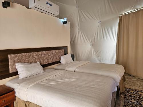 a bedroom with two beds and a window at Sun Luxury Rum Camp in Wadi Rum