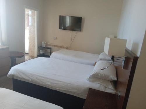 a hotel room with two beds and a flat screen tv at Glastonbury Hotel in Eastbourne