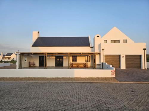 a white house with a black roof at C-Rock Holiday Home Jacobs Bay in Jacobs Bay