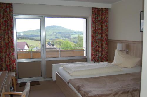 a bedroom with a bed and a large window at Landgasthaus Pfahl in Wershofen
