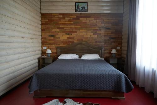 a bedroom with a bed and a brick wall at Argo Guest House in Karakol