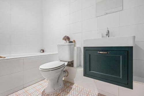 a white bathroom with a toilet and a sink at Lovely 2 bed Streatham apt with outside dining in London