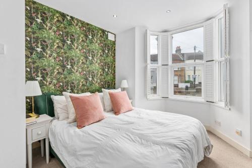 Schlafzimmer mit einem Bett mit weißer Bettwäsche und rosa Kissen in der Unterkunft Lovely 2 bed Streatham apt with outside dining in London