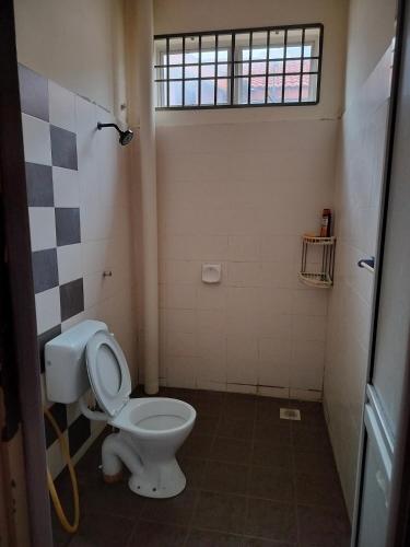 a bathroom with a white toilet and a window at ZR Homestay in Jitra