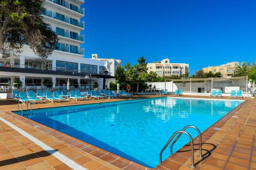 a large swimming pool with blue chairs and a building at Hotel Vibra Riviera in San Antonio Bay