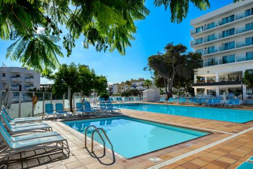 una piscina con sillas y un hotel en Hotel Vibra Riviera, en Bahía de San Antonio