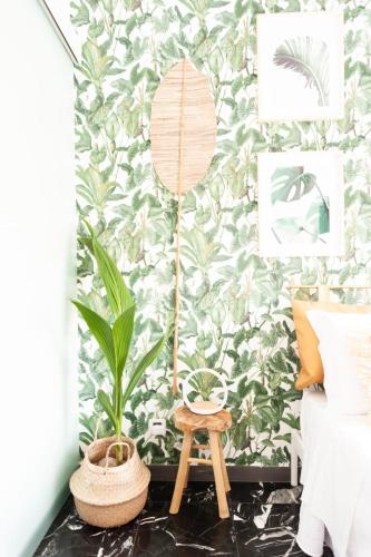 a bedroom with a tropical wallpaper with a plant and a stool at LA CASITA in Alassio