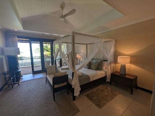 a bedroom with a canopy bed and a balcony at Villa Magnifique by Simply-Seychelles in Eden Island