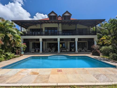 a large house with a swimming pool in front of it at Villa Magnifique by Simply-Seychelles in Eden Island