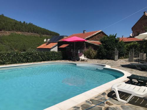 a swimming pool with two chairs and an umbrella at Casas da Nascente in Loriga